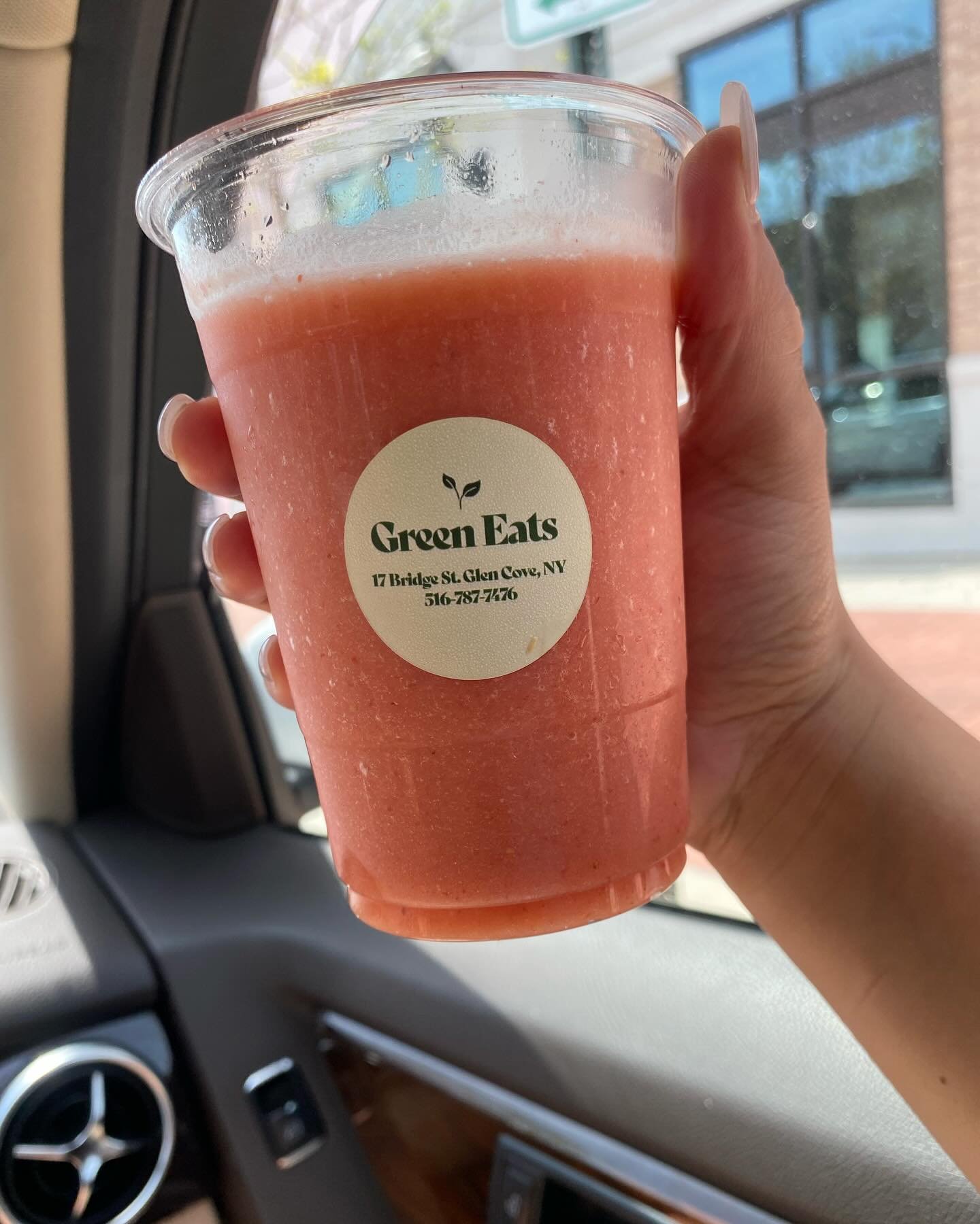 A hand holding a Green Eats smoothie in a branded cup